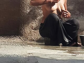 Indian sister-in-law is bathing in the open courtyard of the house, putting a finger in her burrow and rubbing the body, sister-in-law is washing the 